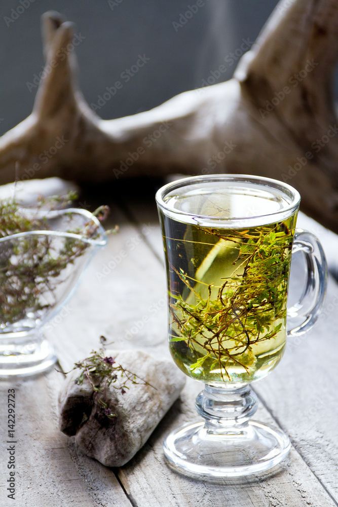 Cup of fresh herbal tea (Dried  Thymus) on wooden table.  Selective focus.