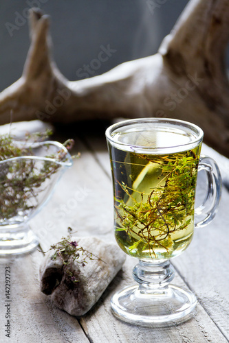 Cup of fresh herbal tea (Dried Thymus) on wooden table. Selective focus.