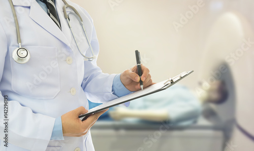 Doctor holding clipboard and take notes the treatment effect with an surgery room at the background. surgeon and medical concept.