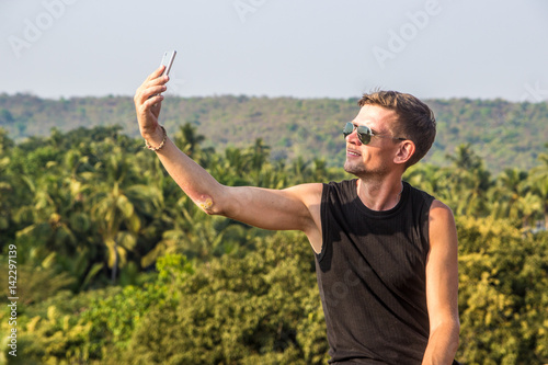 Photography Young man is making a selfie photo from a mobile phone, Goa, India