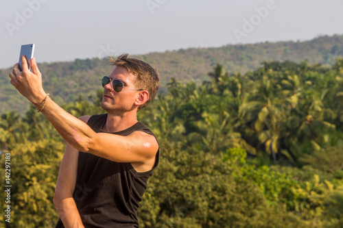 Photography Young man is making a selfie photo from a mobile phone, Goa, India