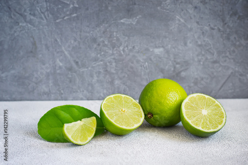 Limes are whole and halves on a gray background, copy space