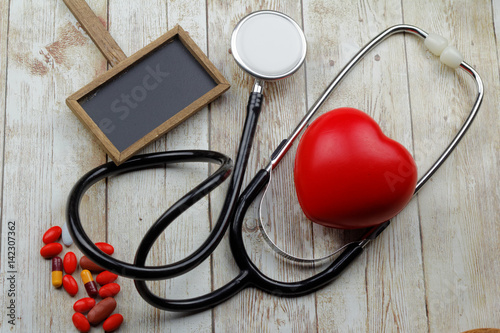 Conceptual with stethoscope and red heart shape on wooden background