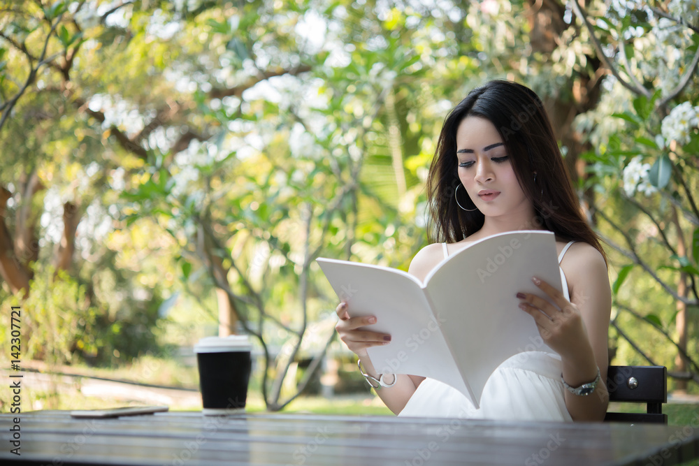 Young beautiful woman sitting and reading the book in the park. Relaxing holiday outdoors. Young beautiful woman sitting and reading the book in the park. Relaxing holiday outdoors.