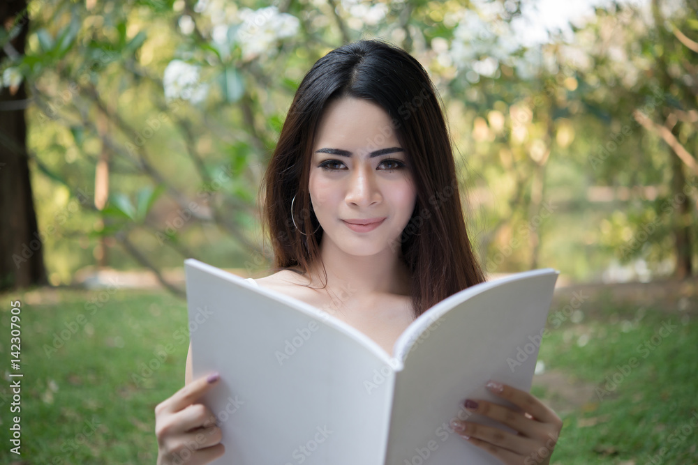 Young beautiful woman sitting and reading the book in the park. Relaxing holiday outdoors. Young beautiful woman sitting and reading the book in the park. Relaxing holiday outdoors.