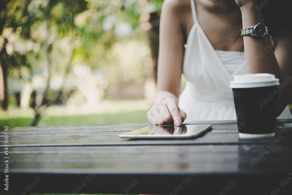 Close up of woman hands holding tablet computer on the wooden table with cup of coffee.