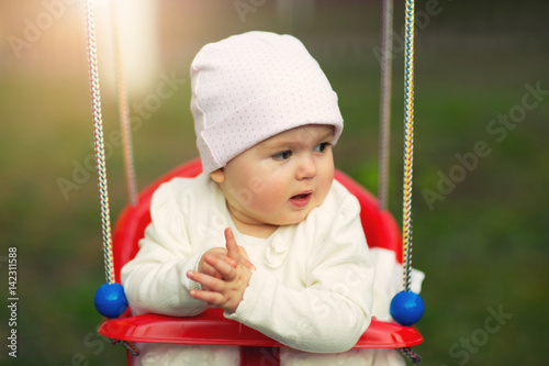 Little baby girl having fun on swing outdoor