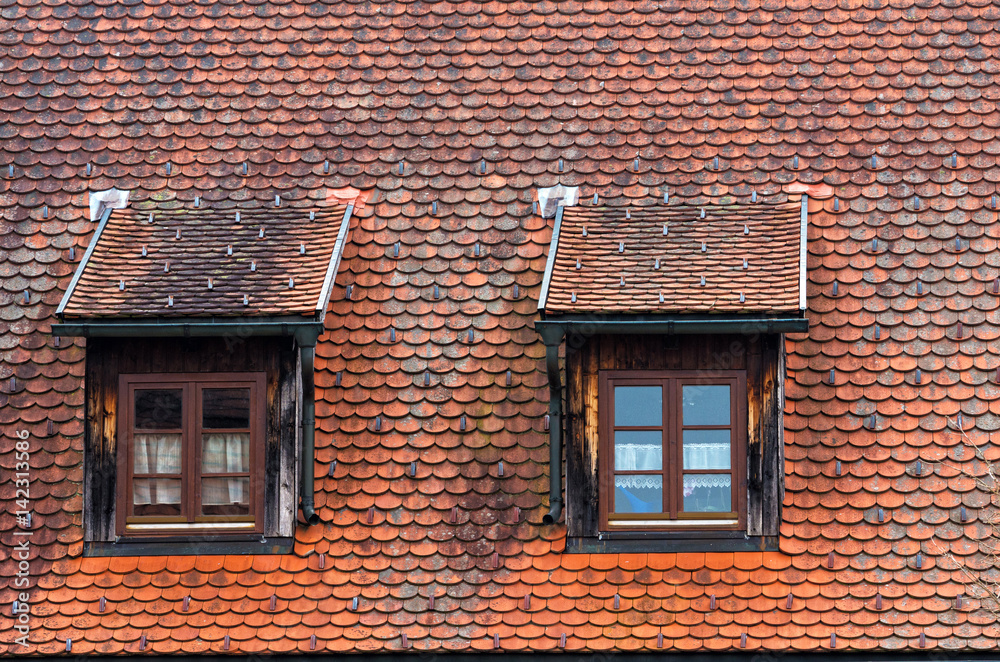 Two windows on mansard roof.Old tiled ceiling of a house in german city. Bavaria, Germany Two windows on mansard roof.Old tiled ceiling of a house in german city. Bavaria, Germany