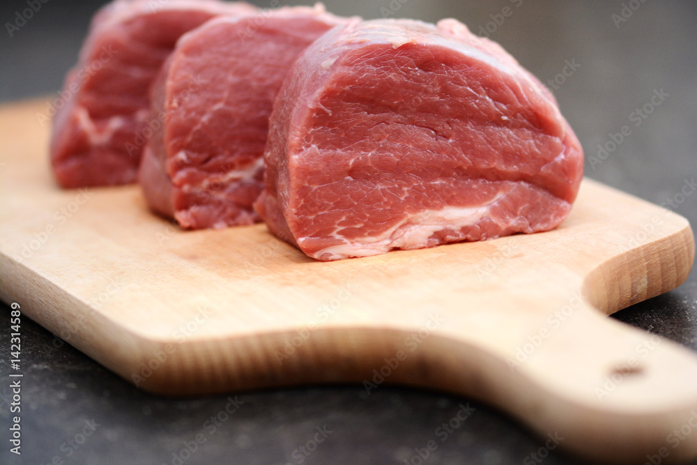 Tasty raw veal or beef meat on wooden cutting board