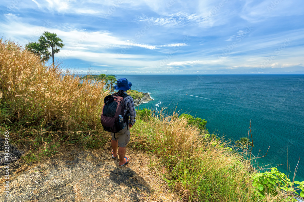 Fototapeta premium Man with hiking equipment walking at Phromthep cape viewpoint in Phuket,.Thailand - success concept