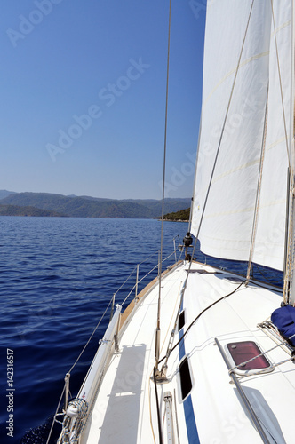 Ultramarine blue water and land viewed from deck of yacht: The blue waters of the turquoise coast in Turkey and land as viewed from the deck of a sailing yacht. © CaitlinWillow