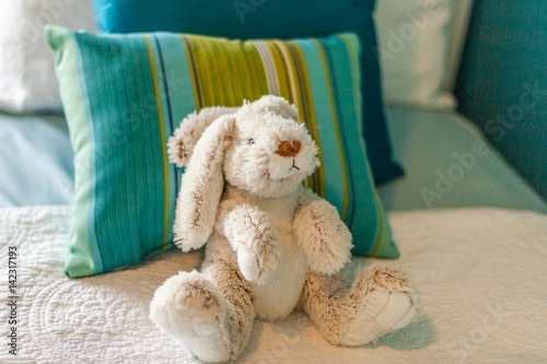 stuffed bunny rabbit on bed with striped pillow