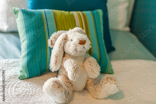 stuffed bunny rabbit on bed with striped pillow photo