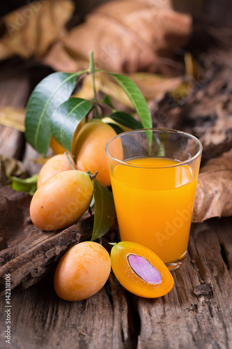 Plango fruit or Marian Plum tropical southeast asia fruit and glass of juice on old wooden background