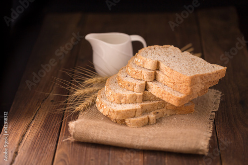sliced whole wheat bread on wooden table, dark background.