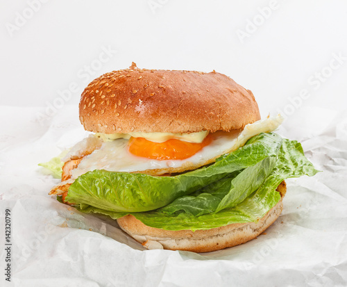 Tasty hamburger with egg on the white paper.
