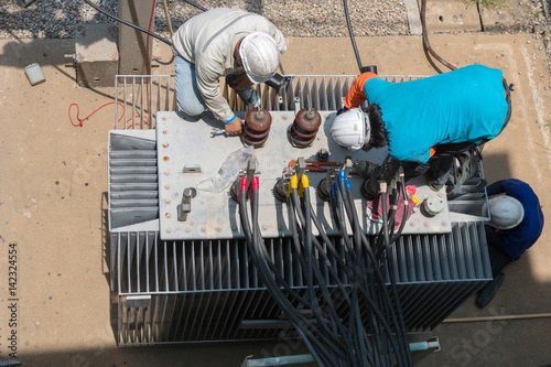 Electrician repairman worker at huge power industrial transformer installation work