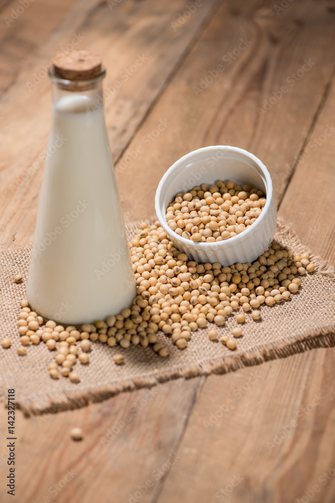 A bottle of soy milk or soya milk and soy beans on wooden table.
