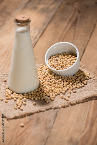 A bottle of soy milk or soya milk and soy beans on wooden table.