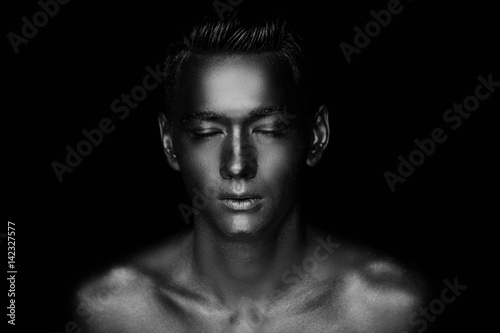 A handsome man of athletic build, completely covered in gold paint.Studio photos., Black and white