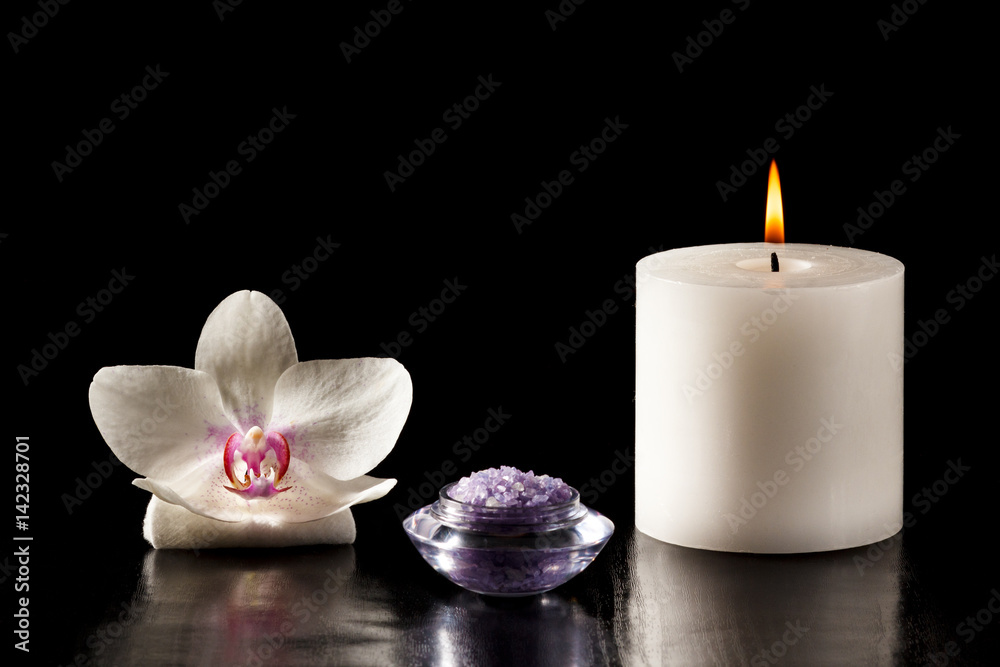 White orchid flower, candle and sea salt for spa procedures on black background
