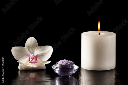 White orchid flower, candle and sea salt for spa procedures on black background