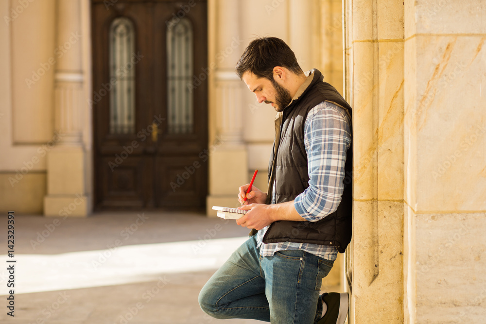 young man with backpack having behind a classic building with big columns