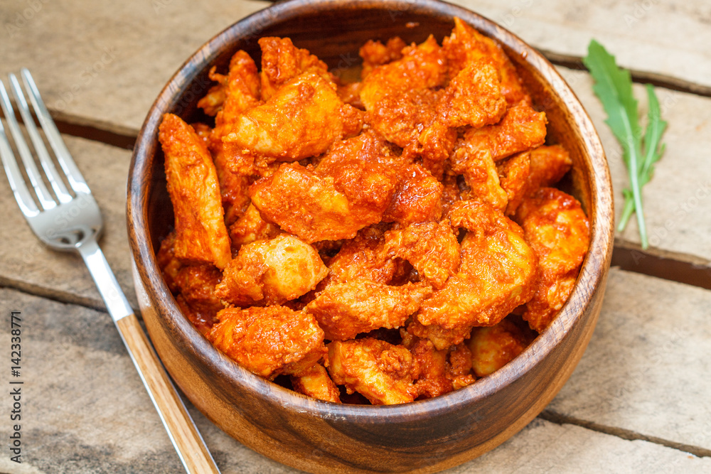Chicken in tomato sauce in a wooden bowl. Chicken in tomato sauce in a wooden bowl.