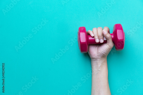 woman hand holding red dumbbell on green background