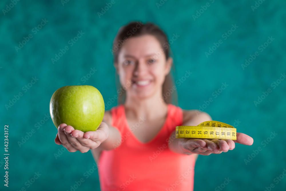 Diet. Healthy happy female with apple and tape measure for diet and weight loss concept - isolated on the turquoise background. Sweets are unhealthy. Junk Food. Dieting, Healthy Eating.
Diet. Healthy happy female with apple and tape measure for diet and weight loss concept - isolated on the turquoise background. Sweets are unhealthy. Junk Food. Dieting, Healthy Eating.