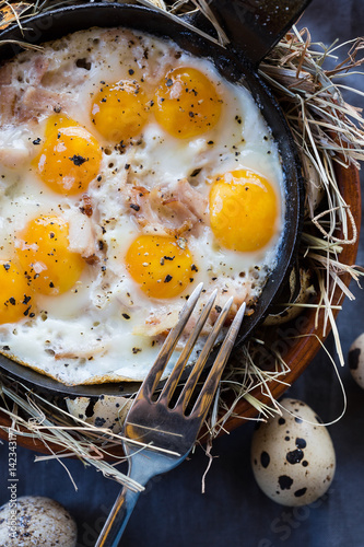 Fried eggs on a cast-iron frying pan. Scrambled eggs from quail eggs on a serving table. Close-up photo