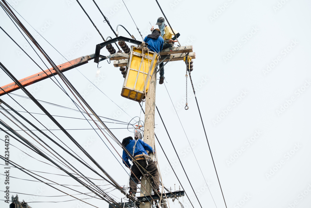 Electrical utility workers repairing problem with power line on the help of truck crane Electrical utility workers repairing problem with power line on the help of truck crane