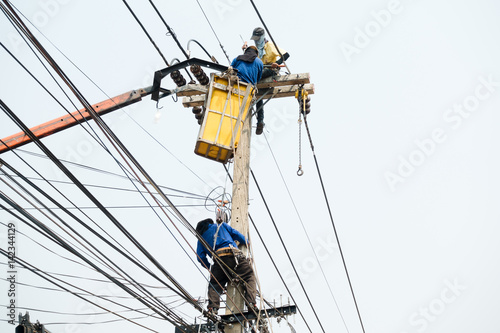 Electrical utility workers repairing problem with power line on the help of truck crane