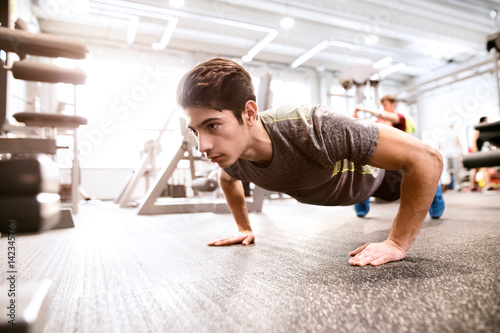 Young fit hispanic man in gym doing push ups