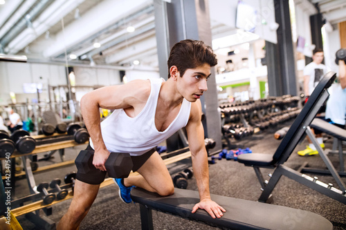 Hispanic man in gym on bench, working out with weights