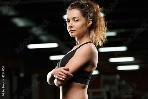 Serious sports lady standing and posing in gym