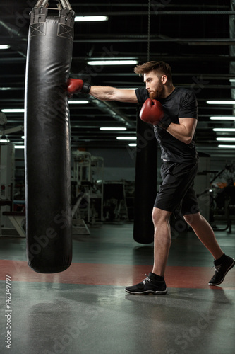 Concentrated young strong sports man boxer make exercises