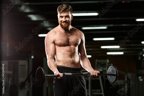 Smiling sports man make sport exercises with barbell