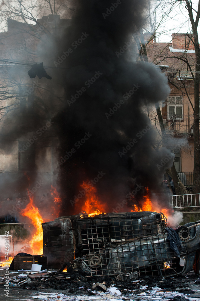 burning car. car destroyed and set on fire during the riots. city center