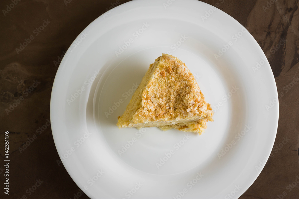 Piece of cake with butter cream on a white plate. Napoleon cake. A delicious dessert. Piece of cake with butter cream on a white plate. Napoleon cake. A delicious dessert.