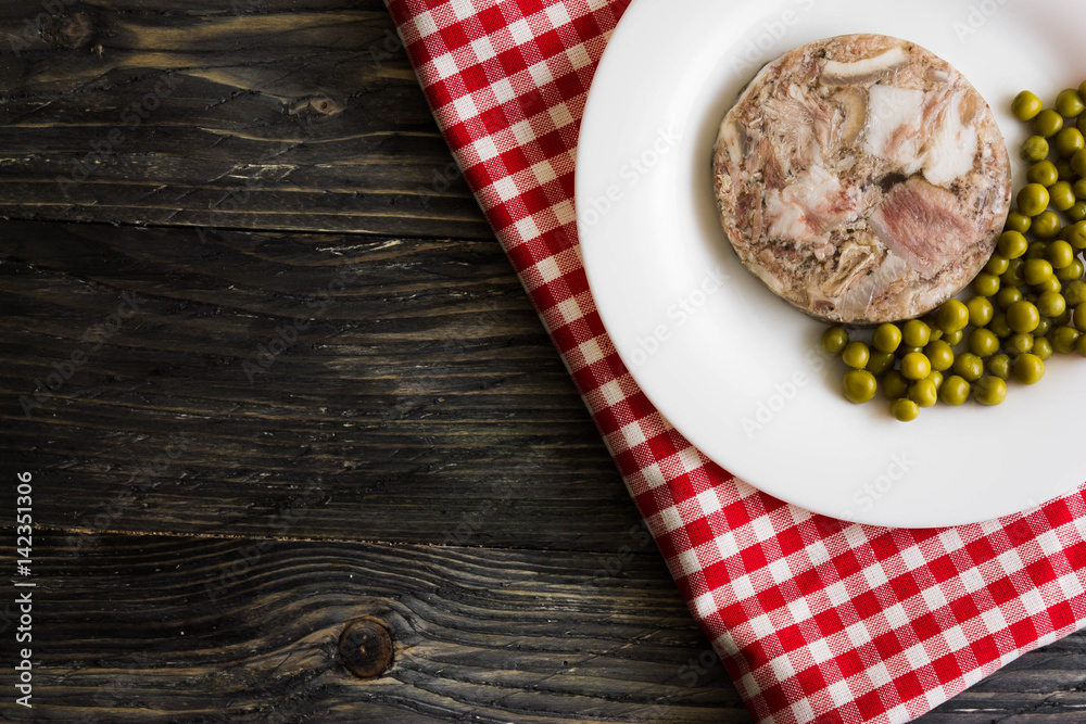 Headcheese with peas on a wooden table. Tasty and nutritious dish.