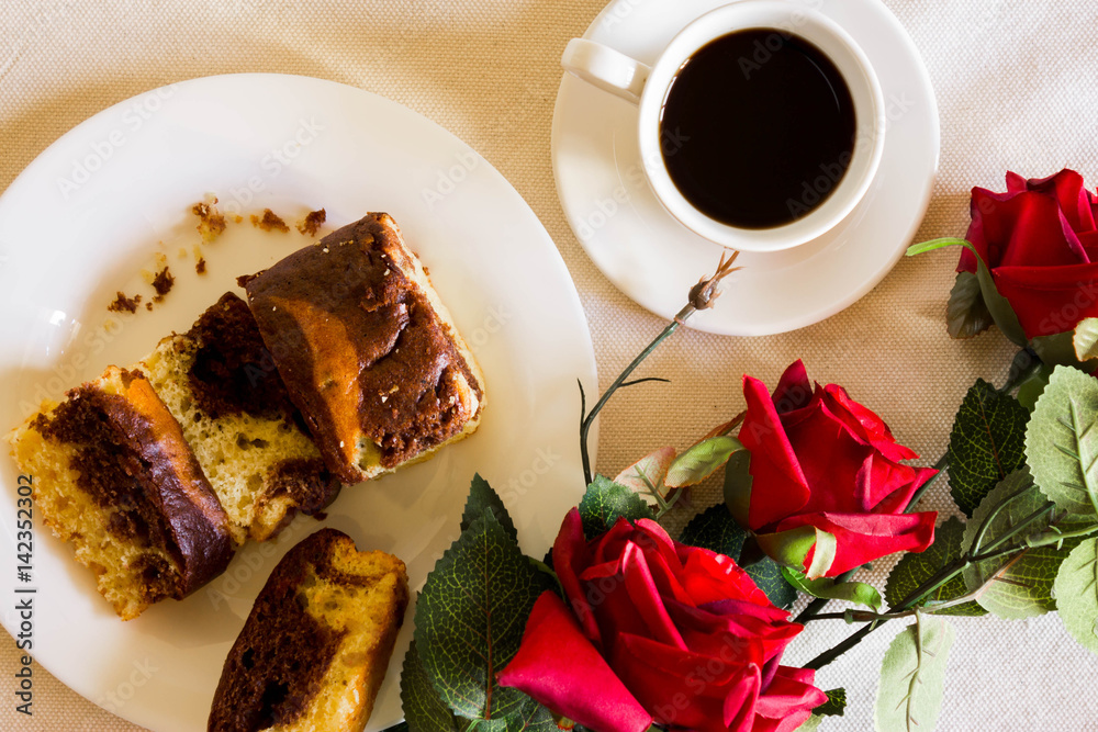 Cake with chocolate on a white plate with coffee and roses Cake with chocolate on a white plate with coffee and roses