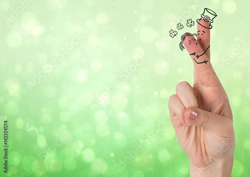 Fingers with faces and shamrocks against green bokeh