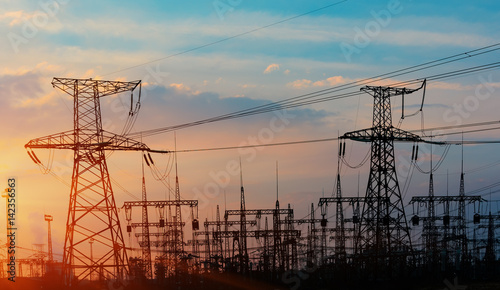 Electric transmission line in rice field during sunset.