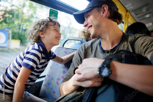 The young man goes by the bus together with the son.