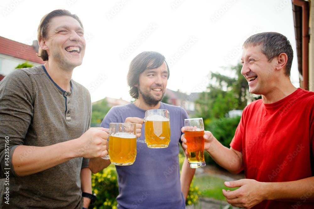 Three young men cheerfully spend time behind a glass of beer Three young men cheerfully spend time behind a glass of beer