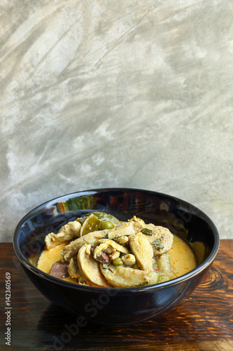 green curry with chicken on wooden table and cement background