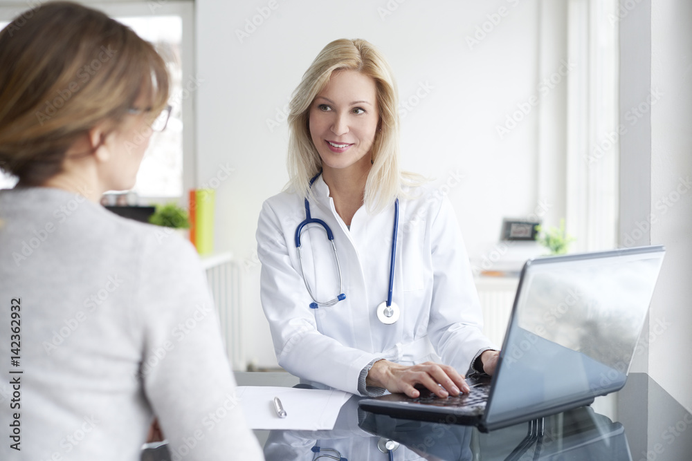 Doctor and her patient. Shot of a middle aged female doctor sitting in front of laptop and consulting with her patient. Doctor and her patient. Shot of a middle aged female doctor sitting in front of laptop and consulting with her patient.
