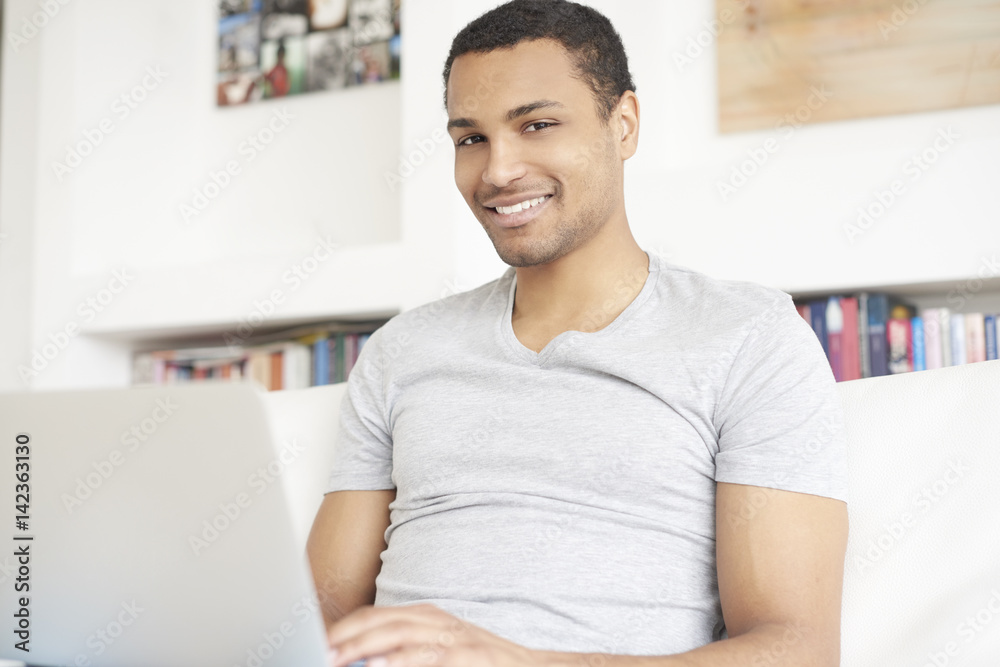 Home office. Shot of an Afro American man using laptop and working in living room.