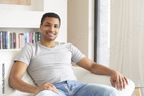 Free Download Weekend at home. Shot of an African American young man relaxing on the sofa. - GFXLoad
